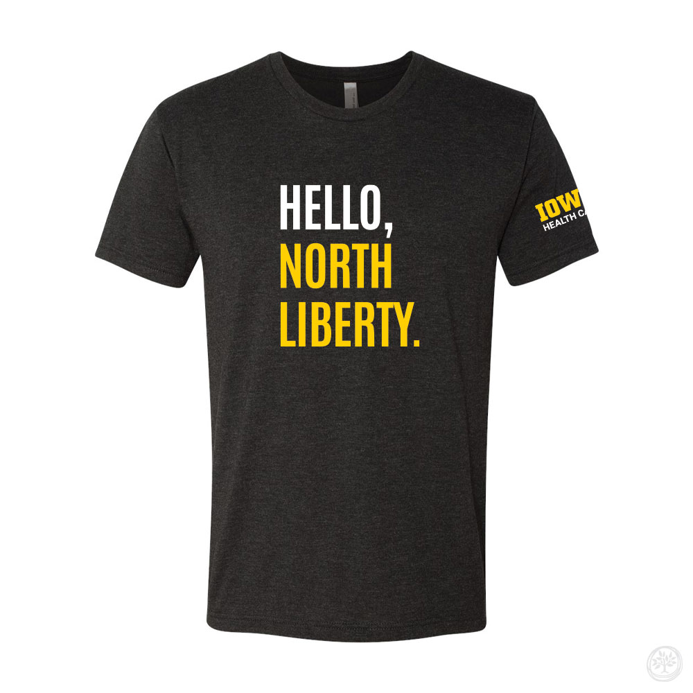 Dark gray t-shirt with bold text on the front reading ‘HELLO, NORTH LIBERTY.’ in white and yellow, and an Iowa Health Care logo printed on the sleeve.