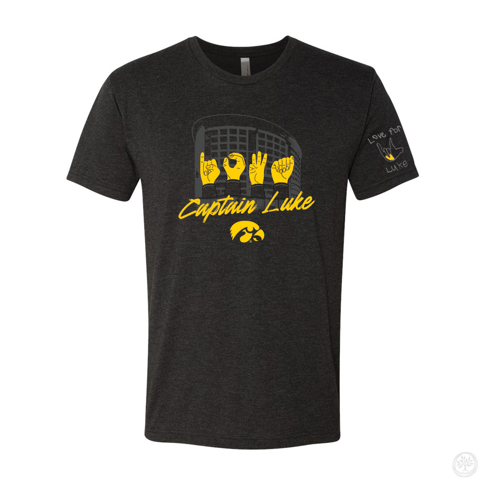 Dark gray t-shirt with a yellow and white design featuring hands spelling out ‘LOVE’ in American Sign Language over Kinnick Stadium, the words ‘Captain Luke,’ and the Iowa Hawkeyes logo. Sleeve text reads ‘Love for Luke’ with a hand sign graphic.
